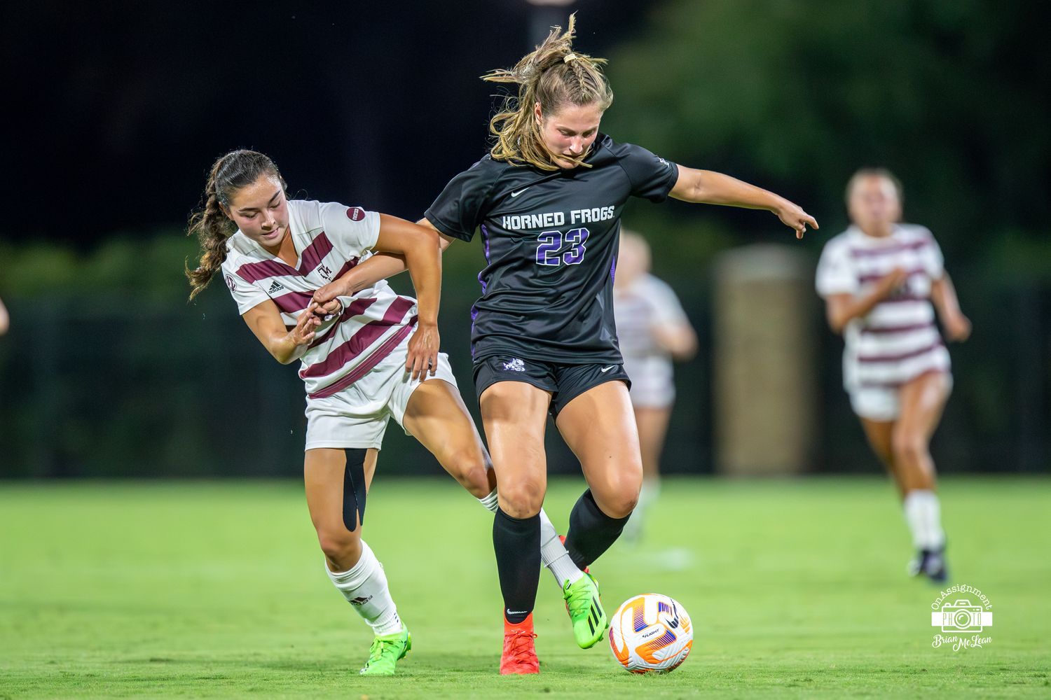 Grace Coppinger (23) tussles with an Aggie defender for the ball.